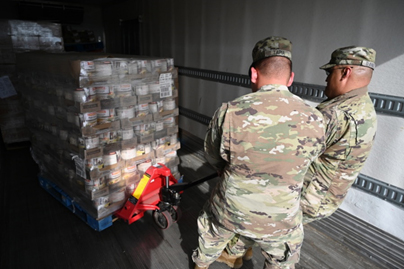 U.S. Army Spc. Jorge Tapia, left, 2-285th Aviation Company wheeled vehicle mechanic, and U.S. Army Sgt. David Daniels, 222 Transportation Company, transportation specialist, help unload pallets of grocery donations at a food bank in Parker, Arizona