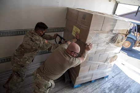 Arizona Army National Guard Pfc. Manuel Pina-Torres, 1-158th Infantry Battalion, infantryman, and Sgt. Joe Branch, 2220 Transportation Company, transportation specialist, unload boxes of groceries from a truck at a food bank in Parker, Arizona