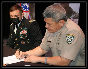 U.S. Army LTC David Hensel (left) watches as Floyd County Sheriff Dave Roberson (right) signs Partnership for Youth Success Agreement