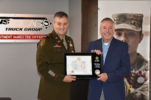 LTC David Culver, hands a plaque highlighting the PaYS partnership to Mr. Joe Cleary, TransChicago Truck Group Chief Operating Officer, following the PaYS signing ceremony.