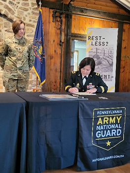 BG Laura McHugh signs the ceremonial signing agreement as SGM Ashley Merrill, Operations SGM, PAARNG RRB looks on.