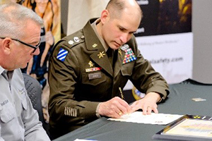 LTC James signs the ceremonial Army PaYS certificate as Mr Clark looks on.