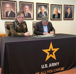 LTC Morris looks on while Mr. Gregory signs the partnership agreement LTC Morris looks on while Mr. Gregory signs the partnership agreement