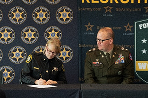 Sheriff LaJoye-Young signs ceremonial MOA as LTC McCart looks on.